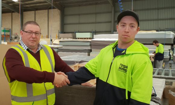 Two people shaking hands for photo in warehouse