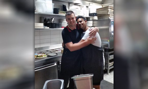 Two kitchen workers posing for photo and smiling