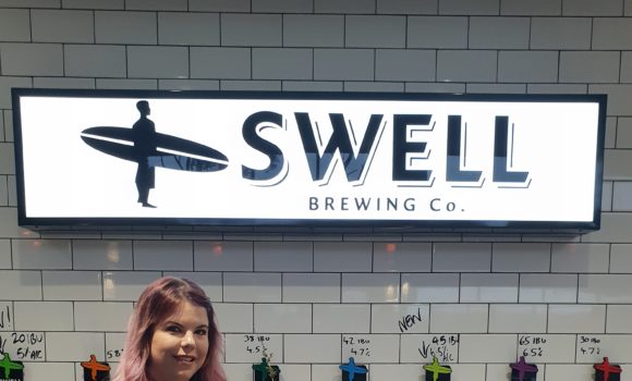 Lady smiling for photo at Swell Brewing Co posing with flowers