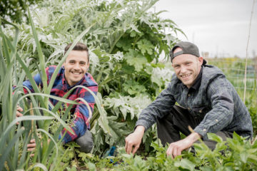 Two people posing for photo in a vegetable garden