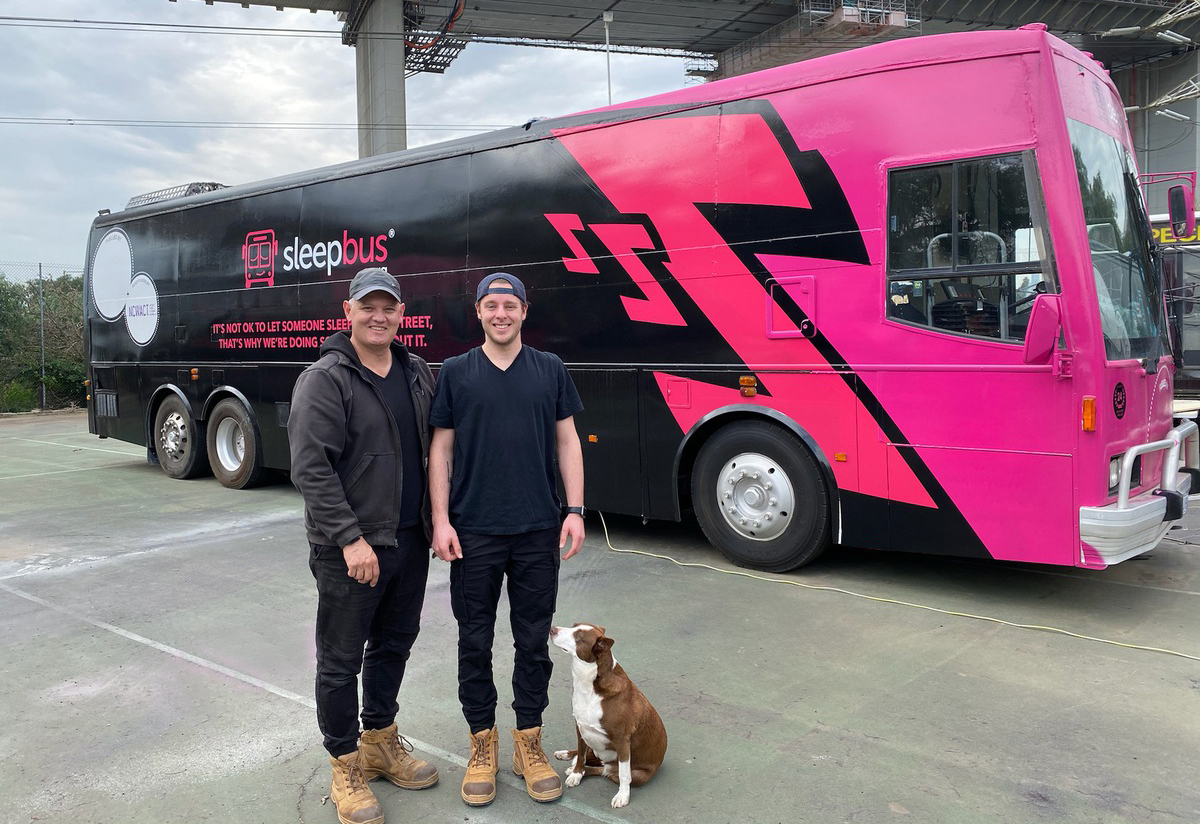 Two people standing in front of a bus posing for a photo
