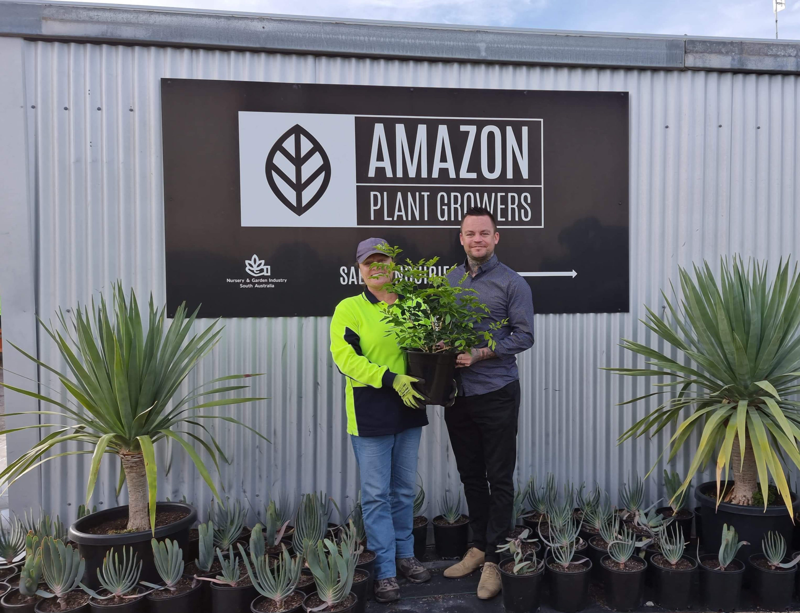 Two people posing for photo in front of Amazon plant growers
