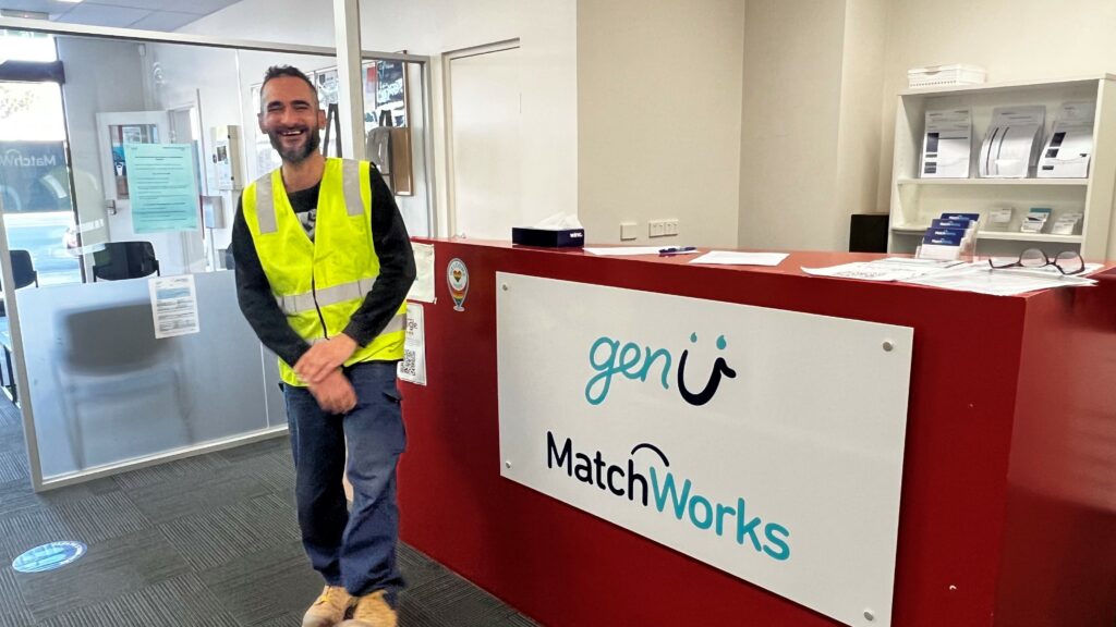 Portrait of Walid, smiling and wearing his work vest at MatchWorks office. 
